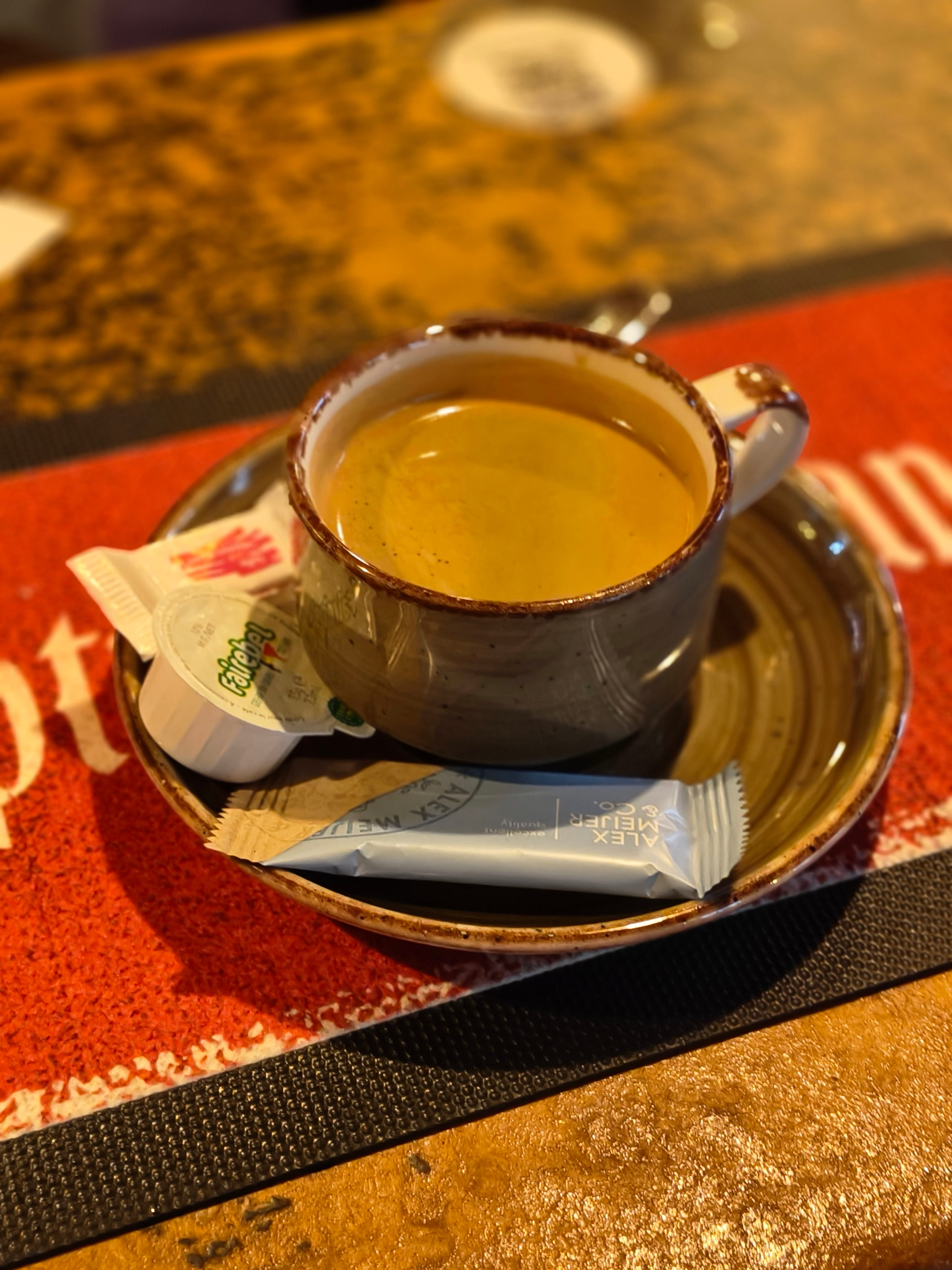 Een dampende kop koffie geserveerd op de houten toog van de kroeg